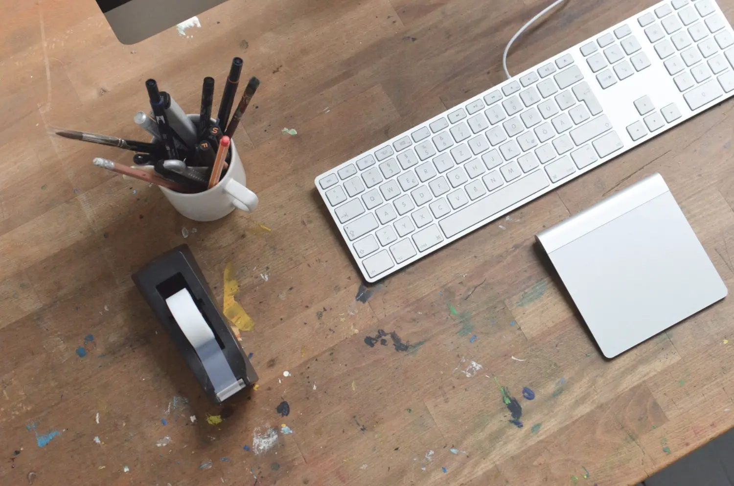 Aufgeräumter Schreibtisch von oben mit Tastatur und Notizblock